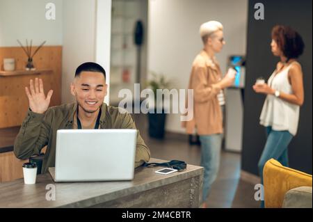 Joyeux employé de bureau communiquant sur Skype pendant la pause café Banque D'Images