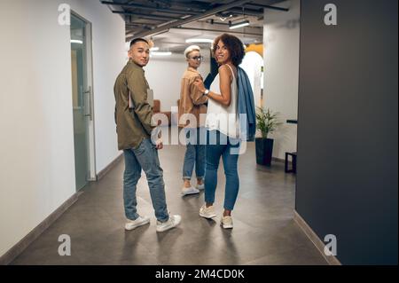 Jeune équipe multinationale de travailleurs d'entreprise dans le couloir de bureau Banque D'Images