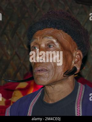 Mon district, Nagaland, Inde - 11 25 2013 : Portrait intérieur d'un homme de la tribu Naga Konyak d'âge moyen portant des boucles d'oreilles spectaculaires de chèvre ou de sélow Banque D'Images