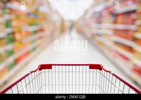Panier en vue de l'allée avec des étagères de supermarché produit un arrière-plan flou abstrait Banque D'Images
