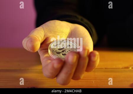 monnaie chinoise argent 10 yuan panda en main sur table et fond coloré Banque D'Images