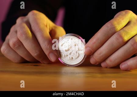 monnaie chinoise argent 10 yuan panda dans les mains sur la table et fond coloré Banque D'Images