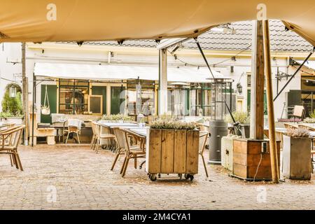 une salle à manger extérieure avec tables et parasols sur la terrasse extérieure, entourée de plantes et de jardinières en pots Banque D'Images