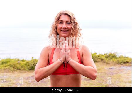 Portrait d'une femme sportive souriante faisant du yoga dans un parc Banque D'Images