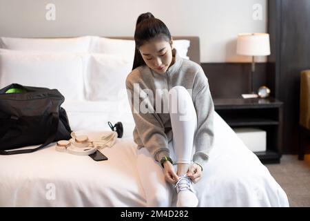 Une jeune femme chinoise qui noue ses lacets dans sa chambre à coucher Banque D'Images