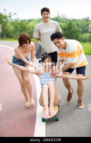 De jeunes amis chinois heureux qui profitent du skateboard en plein air Banque D'Images