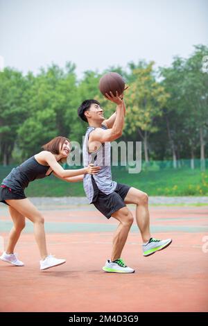 Joyeux jeune couple chinois jouant au basket-ball en plein air Banque D'Images