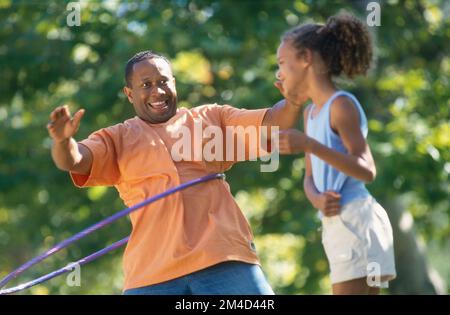 Père afro-américain et fille dehors utilisant un hula hoop Banque D'Images