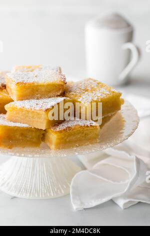 Carrés de citron doux faits maison sur un socle arrosé de sucre en poudre. Banque D'Images