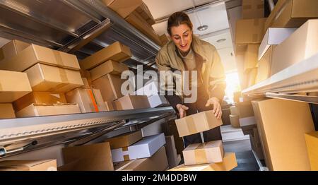 une femme de livraison triait les colis de sa camionnette pour les livrer à un client. Image de concept de livraison par messagerie Banque D'Images