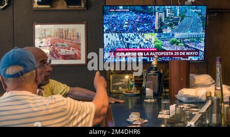 Des hommes dans un bar à Buenos Aires, en Argentine regardent la couverture télévisée du bus à toit ouvert transportant l'équipe Argentine gagnante de la coupe du monde de la FIFA dans la ville - avant Banque D'Images