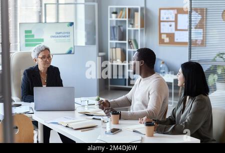 Portrait d'une femme mûre dirigeant une réunion avec des collègues au bureau, dans l'espace de copie Banque D'Images