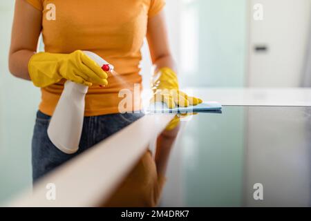 Table de nettoyage de femme de ménage non reconnaissable dans la cuisine avec un spray et un chiffon Banque D'Images