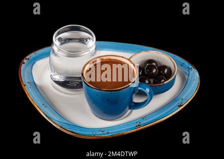 Café turc dans une tasse bleue, chocolat sur un plateau de service en porcelaine, eau et une tasse de café. Isolé sur fond noir. Menu au café, détente Banque D'Images