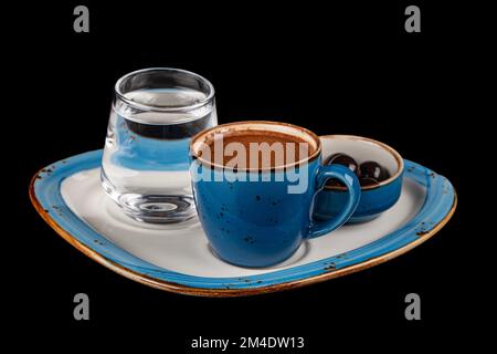 Café turc dans une tasse bleue, chocolat sur un plateau de service en porcelaine, eau et une tasse de café. Isolé sur fond noir. Menu au café, détente Banque D'Images