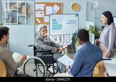 Portrait d'une femme d'affaires mûre utilisant un fauteuil roulant tout en donnant une présentation en réunion Banque D'Images