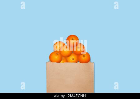 Oranges dans un sac en papier. Sur fond bleu. Banque D'Images
