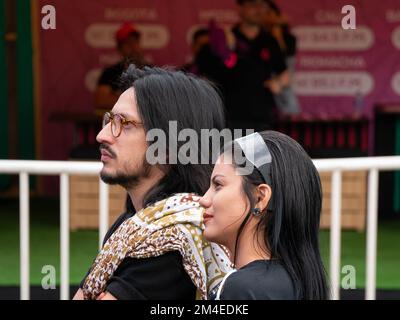 Medellin, Antioquia, Colombie - 14 novembre 2022: Un jeune homme colombien avec des lunettes et une femme à cheveux noirs regardent un événement dans un parc Banque D'Images