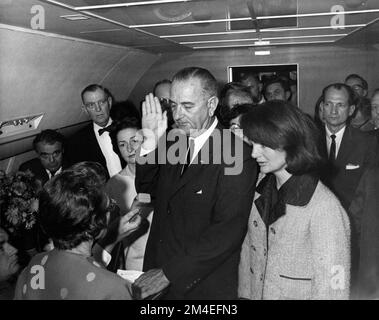 La photo emblématique de Lyndon B. Johnson, prise par Cecil Stoughton, est assermentée en tant que président de la Force aérienne One et se prépare à partir de Love Field à Dallas. Jacqueline Kennedy (à droite), toujours dans ses vêtements en lambeaux de sang (non visibles ici), regarde. Banque D'Images