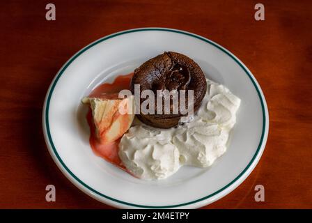 Un brownie au chocolat servi sur une assiette blanche avec de la crème fouettée et de la glace à la vanille Banque D'Images