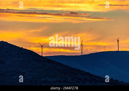 Une vue fascinante sur les moulins à vent au sommet des montagnes verdoyantes pendant un coucher de soleil pittoresque en Croatie Banque D'Images