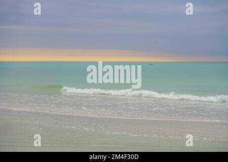 Coucher de soleil derrière les nuages sur l'eau turquoise et le sable blanc à l'île Anna Maria en Floride Banque D'Images