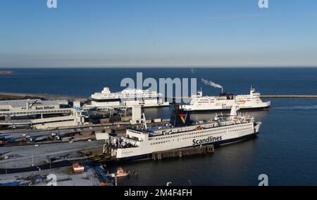 Fehmarn, Allemagne. 16th décembre 2022. Trois ferries de la compagnie maritime danoise Scandlines sont vus dans le port de ferry de Puttgarden sur l'île de Fehmarn. A côté du port de ferry, la fosse d'excavation pour le portail du tunnel de Fehmarnbelt est en cours de construction (vue aérienne avec un drone). Le tunnel routier et ferroviaire de 18 kilomètres relie l'île de Fehmarn à l'île danoise de Loland à partir de 2029. Selon Femern A/S, le coût est de 7,1 milliards d'euros. Credit: Christian Charisius/dpa/Alay Live News Banque D'Images