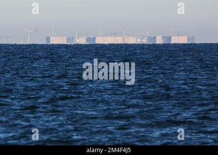 Fehmarn, Allemagne. 16th décembre 2022. L'usine d'éléments de tunnel pour la construction du tunnel de la mer Baltique est visible à l'horizon au-dessus de la mer Baltique. Le tunnel routier et ferroviaire de 18 kilomètres relie l'île de Fehmarn à l'île danoise de Loland à partir de 2029. Selon Femern A/S, le coût est de 7,1 milliards d'euros. Credit: Christian Charisius/dpa/Alay Live News Banque D'Images