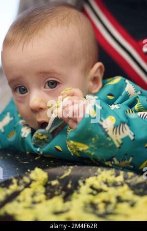 Bébé se gâte tout en se nourrissant avec une cuillère Banque D'Images