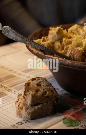 Plat portugais typique avec du poisson à la morue, de l'huile d'olive et des pommes de terre servi dans une marmite en argile sur une table rustique traditionnelle Banque D'Images