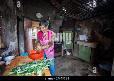 Femme cuisant sur feu ouvert dans une petite cuisine à l'ancienne dans une maison de campagne Banque D'Images