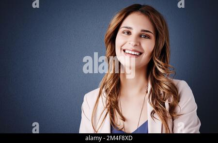 État d'esprit positif, résultats positifs. Portrait en studio d'une jeune femme d'affaires attrayante et confiante se posant sur un fond bleu foncé. Banque D'Images