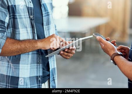 L'entreprise moderne est connectée. Gros plan de deux concepteurs méconnaissables utilisant des appareils numériques dans un bureau. Banque D'Images