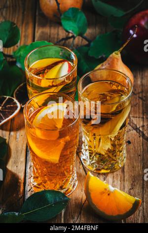 Verres à cidre : boissons aux pommes, aux poires et à l'orange. Cocqueue de fruit fermentée à faible teneur en alcool sur fond de table en bois avec feuilles Banque D'Images