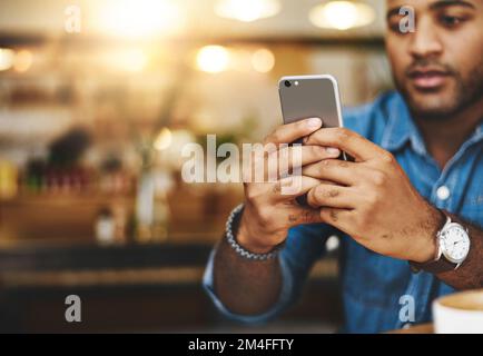 HES a obtenu toutes les connexions. Gros plan d'un jeune homme utilisant un téléphone portable dans un café. Banque D'Images