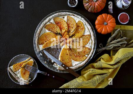 Tarte à la citrouille avec fromage et épices sur fond sombre, vue de dessus, espace de copie Banque D'Images
