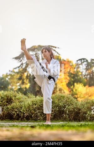 Chasseur en kimono et ceinture noire debout en position de karaté à l'extérieur dans la nature. Sports et arts martiaux concept. Banque D'Images