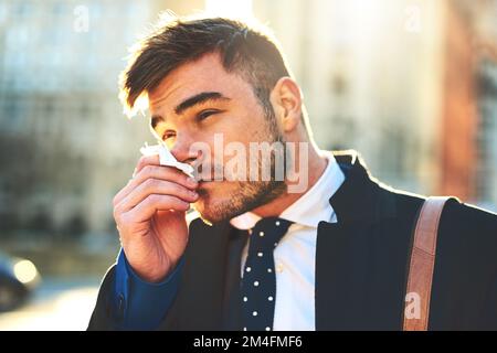 Heureusement, j'ai rempli les mouchoirs avant de sortir. un jeune homme irrité soufflant son nez avec un tissu tout en marchant dans les rues animées de la Banque D'Images