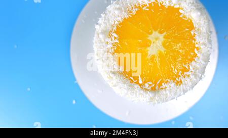 Gâteau aux copeaux d'orange et de noix de coco tournant sur fond bleu Banque D'Images