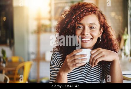 Mon bonheur est alimenté par le café. Portrait d'une jeune femme attrayante appréciant une tasse de café dans un café. Banque D'Images