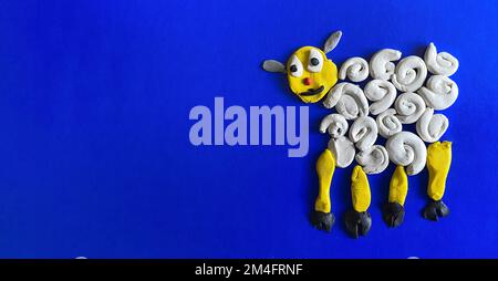 Mouton moulé à partir de la plasticine sur fond bleu, foyer sélectif. Drôle d'animal de plasticine. Sculpter de l'argile. Concept d'activité créative, chil Banque D'Images