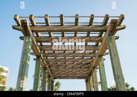 Vue d'un toit de pergola en grille de bois d'en dessous contre le ciel à destin, Floride. Toit pergola avec piliers verts en sauge et vue sur la paume tr Banque D'Images