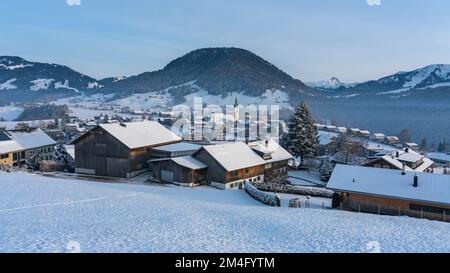 Weekliches Panorama mit Verchneiter Landschaft, Blick über Dorf im Winter mit Schnee auf Wiese und Wälder, Berge des Bregenzerwald im hintergrund, Banque D'Images