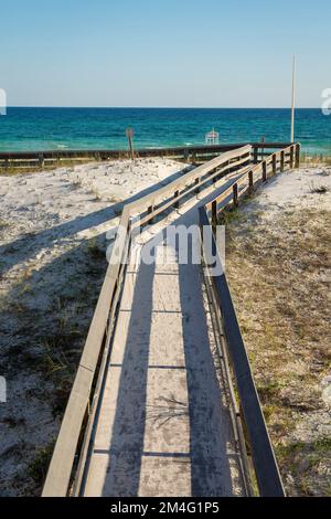 Vue de dessus d'une promenade en planche sur le sable blanc avec de l'herbe en direction de la plage à destin, Floride. Sentier en bois recouvert de sable avec rambardes et vue Banque D'Images