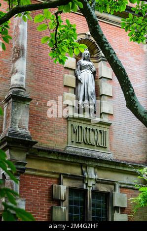 Statue de la reine Victoria tenant une orbe et un arnaque au-dessus d'un bâtiment situé à l'école publique du Winchester College, dans le Hampshire. Date des chiffres romains Banque D'Images
