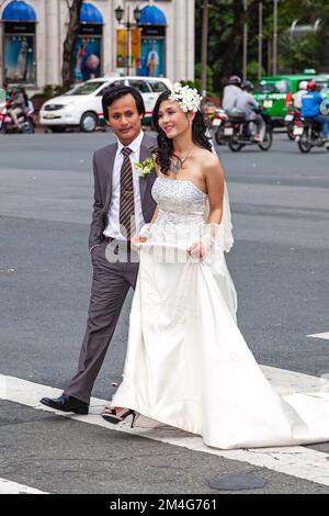 Couple vietnamien en face de la rue à travers la circulation pour la photo de mariage, centre de Ho Chi Minh ville, Vietnam Banque D'Images