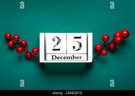 Date de la veille de Noël sur cube blanc en bois Calendrier, 25 décembre, avec décorations de Noël et baies rouges sur fond vert carte de Noël date de Noël. Banque D'Images
