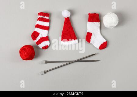 Chaussettes de Noël tricotées rouges et blanches et chapeau de Père Noël avec une boule blanche et rouge de fils et aiguilles à tricoter. Décorations de Noël, kni d'hiver Banque D'Images