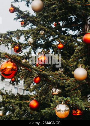 Gros plan d'un sapin de noël à la décoration festive avec des boules rouges et beiges sur fond flou. Banque D'Images