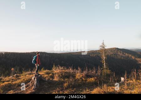 Le randonneur actif apprécie l'impression d'atteindre le sommet de la montagne au lever du soleil. Un randonneur est éclairé par le soleil du matin et bénéficie de la vue sur valle Banque D'Images